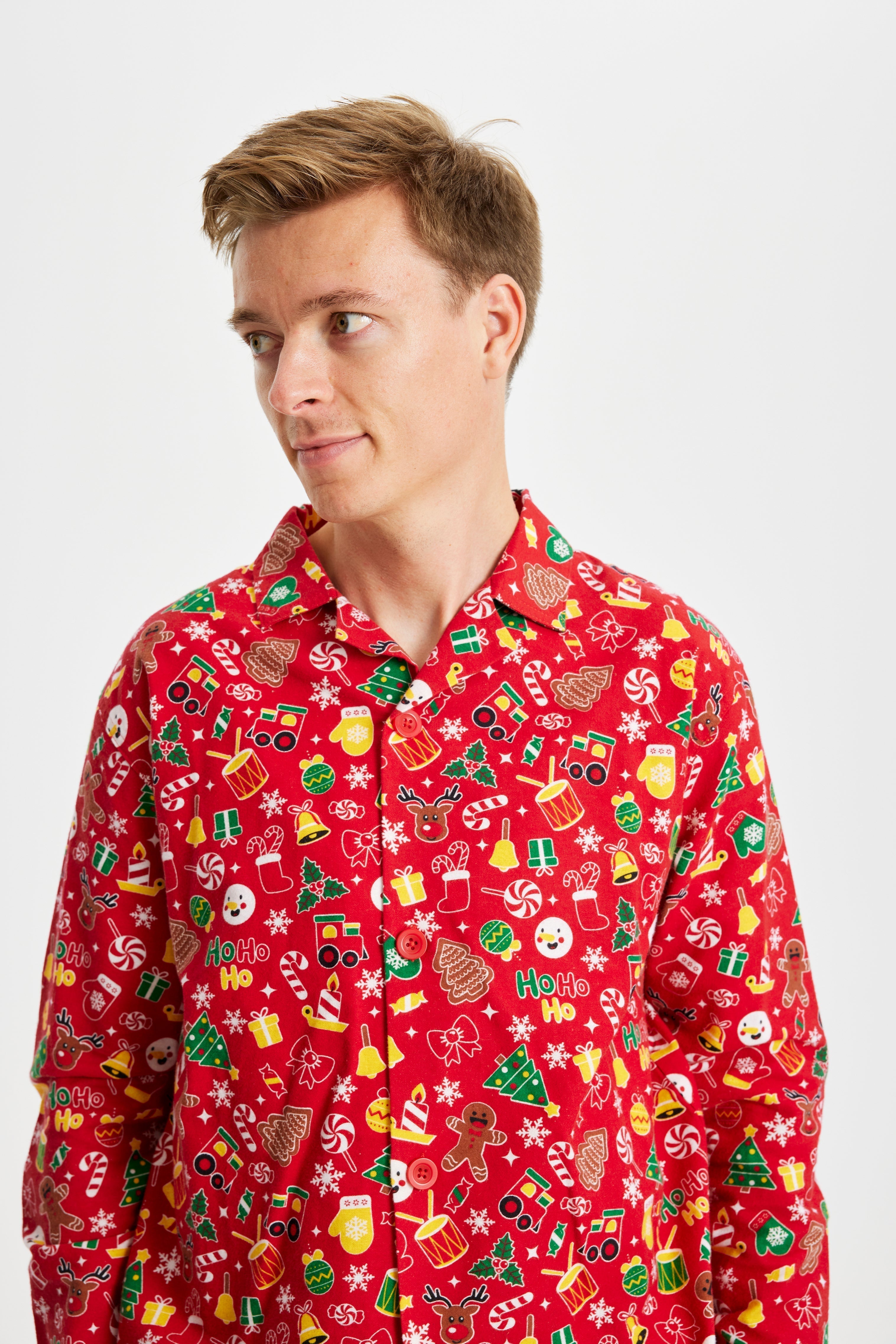 Un homme regardant sur le côté portant un pyjama de Noël rouge avec un imprimé de Noël.